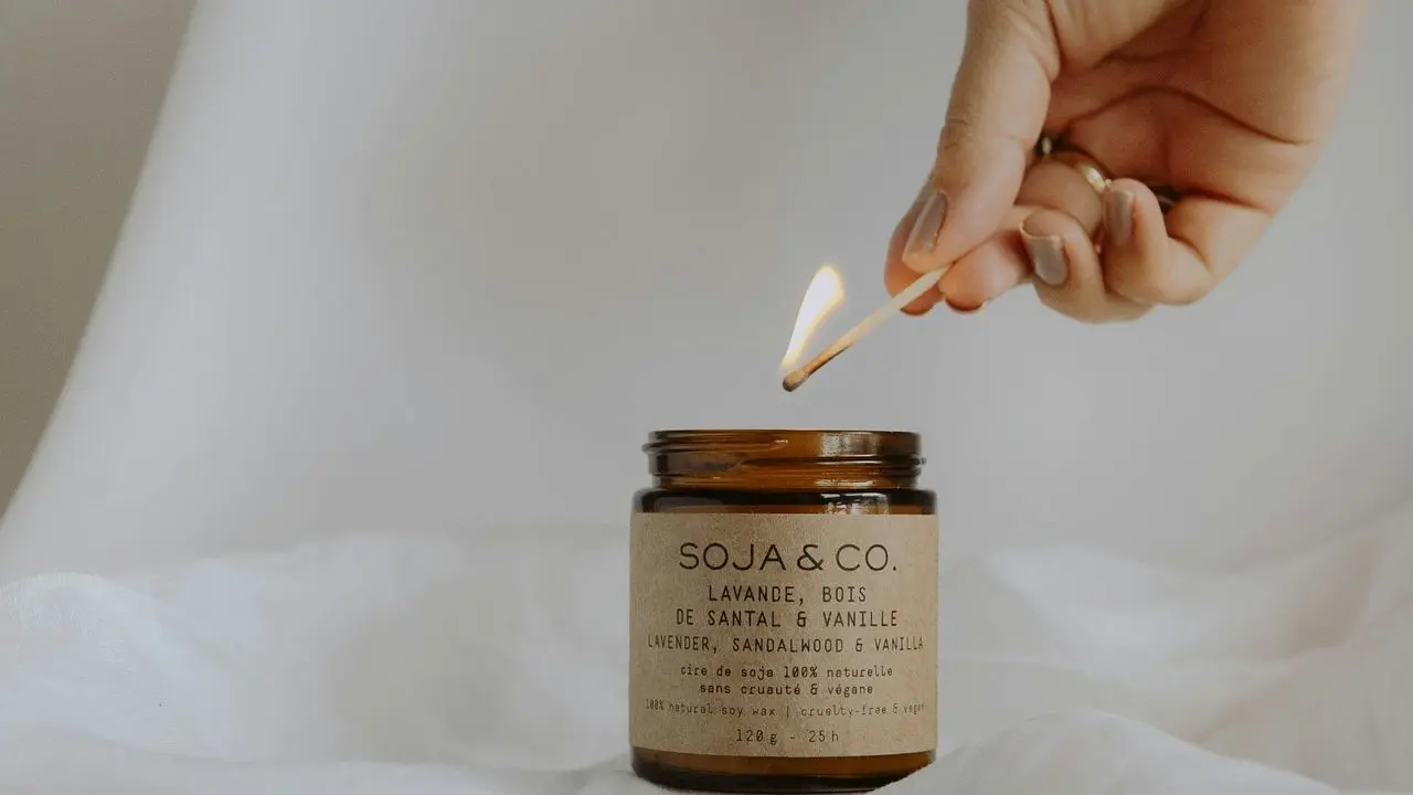 person holding white and black labeled glass jar